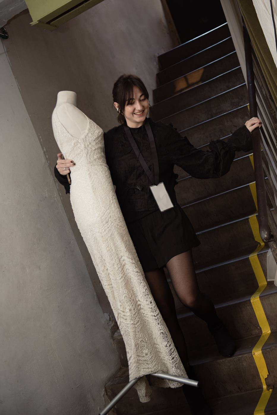Valentina Buffa sosteniendo un vestido de novia de encaje en un backstage de moda